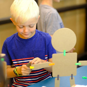 young boy learning STEM with cardboard and connector modeling set